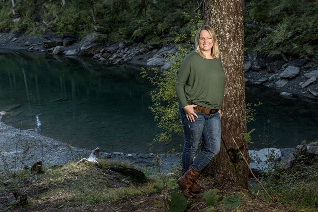 Nicole Gansner lehnt an einem Baum am türkisfarbenen See
