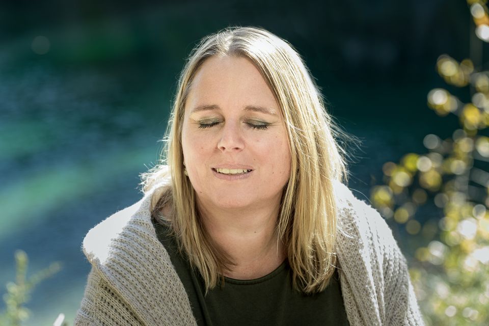 Nicole Gansner mit geschlossenen Augen am See – Ruhe und Innenschau