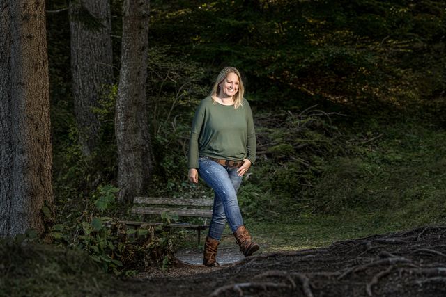 Nicole Gansner spaziert lächelnd durch den Wald